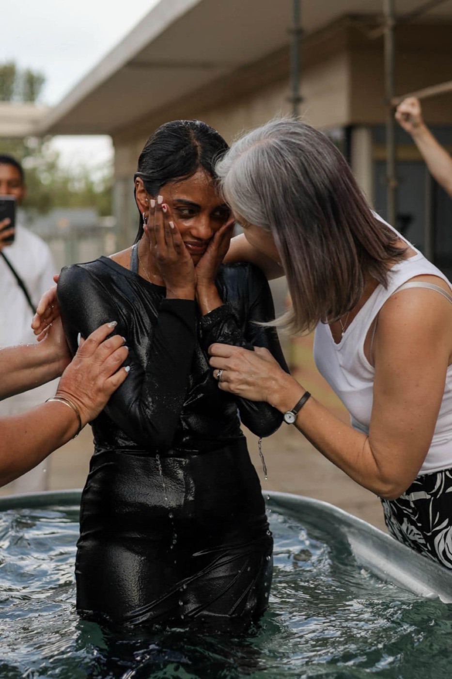 A woman being supported after her baptism