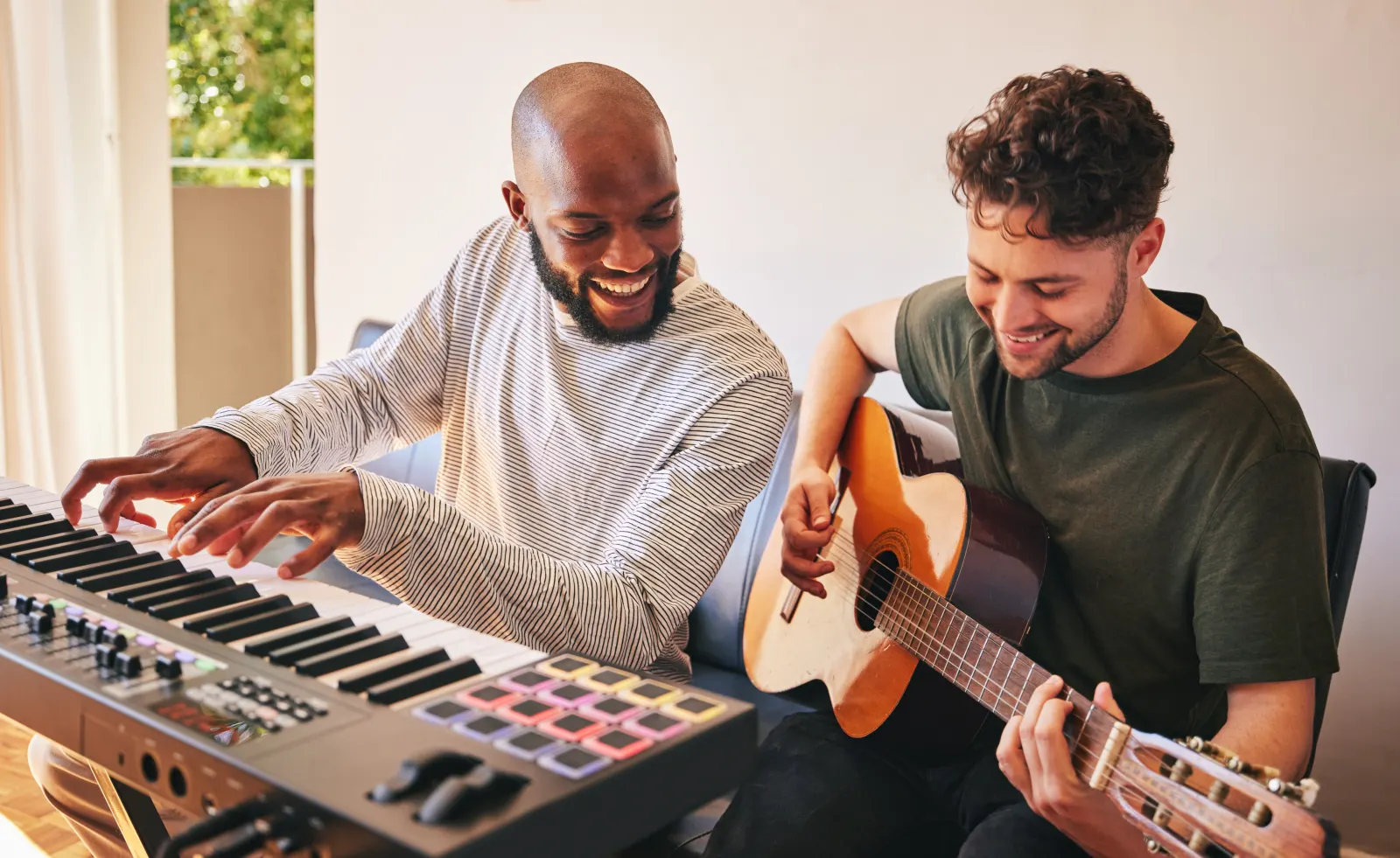 Two musicians playing keyboard and guitar together in a home studio